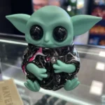 Front view of the Grogu Baby Yoda grinder sitting on a glass display counter.
